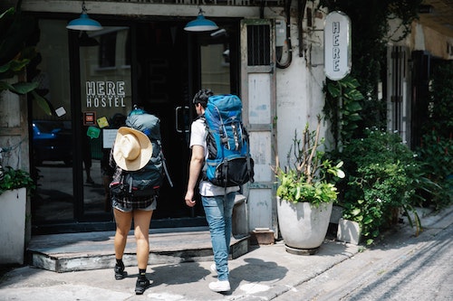 Two backpackers entering a city hostel.