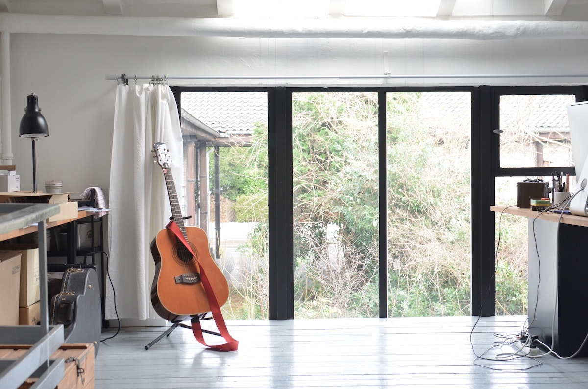 An acoustic guitar resting on a stand in a home office